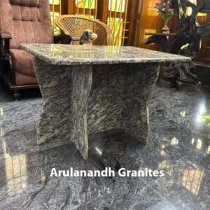 Polished granite table with beveled edges and an interlocking three-slab base displayed in a showroom setting.