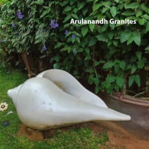 Elegant white shell sculpture placed in a landscaped garden, surrounded by potted plants and greenery.